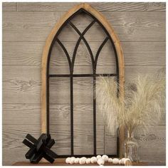 an arched window with some feathers on the shelf next to it and a vase filled with flowers