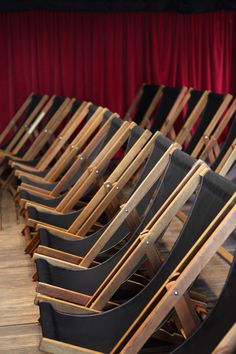 rows of empty wooden chairs in front of a red curtain