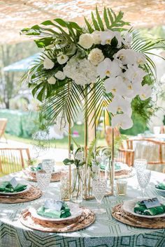 a table set with flowers and greenery for a wedding reception at the resort or spa