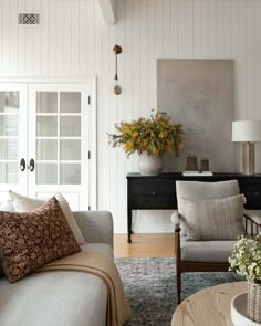 a living room filled with furniture and flowers on top of a coffee table in front of a doorway