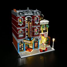 a lego model of a building with lights and decorations on the front, in dark room