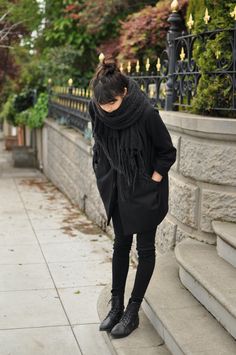 a woman is standing on the steps wearing black boots and a scarf around her neck