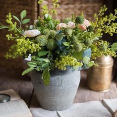 a vase filled with flowers sitting on top of a wooden table next to an open book