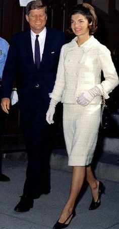 a man and woman are walking down the street in formal attire, one is wearing a white dress