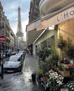 the eiffel tower is seen in the background as cars are parked on the street