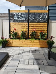 an outdoor patio with wooden fence and planters on the side, surrounded by stone pavers