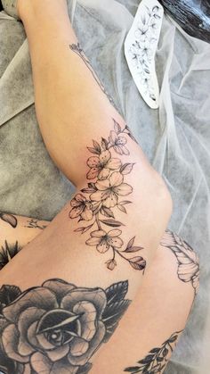 a woman's legs with tattoos and flowers on them