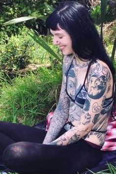 a woman with tattoos sitting in the grass