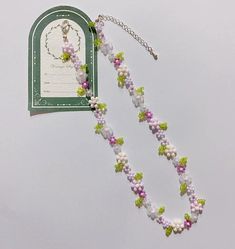 a necklace with flowers on it and a tag hanging from the back of it's chain