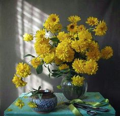 a vase filled with yellow flowers sitting on top of a green table next to scissors