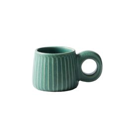 a green coffee cup sitting on top of a white table