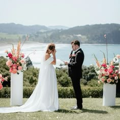 a man and woman standing next to each other in front of some vases with flowers