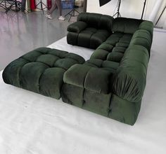 a large green couch sitting on top of a white floor next to a black chair