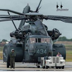 two men standing in front of a large helicopter