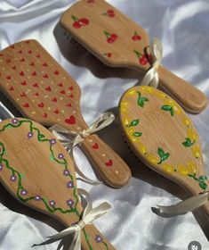 three wooden spoons with designs on them sitting on a white cloth covered tablecloth