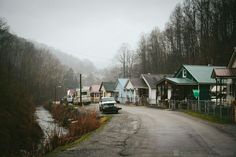 a car parked on the side of a road in front of some houses and trees