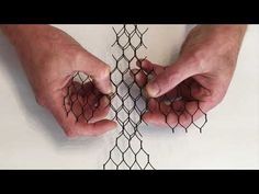 two hands are holding some wire on top of each other, with one hand over the net