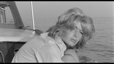 black and white photograph of a woman leaning on the side of a boat looking off into the distance