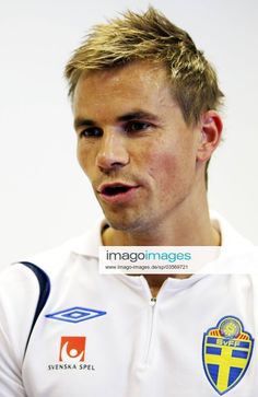 a man with blonde hair is wearing a white shirt and has a cross on his chest