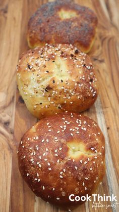 three bagels sitting on top of a wooden cutting board next to eachother