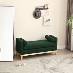 a green couch sitting in front of a mirror next to a wall mounted coat rack