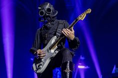 a man in a gas mask playing guitar on stage