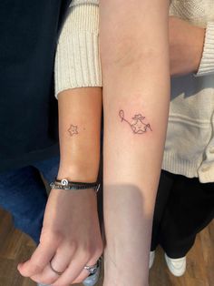 two people holding hands with tattoos on their arms, one has a star and the other has a fish