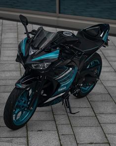 a blue and black motorcycle is parked on the sidewalk