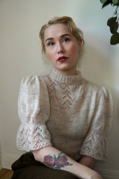 a woman sitting on the floor wearing a sweater