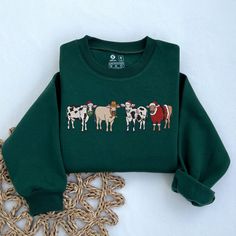 EMBROIDERED Christmas Cow Sweatshirt, Cow Lover Gift, Funny Christmas Shirt, Holiday Sweater, Farm Christmas Shirt, Christmas Crewneck Product Details: * T-Shirts: Made from 100% premium cotton, our T-shirts are soft, comfortable, and durable. * Sweatshirts: Crafted from a blend of 50% cotton and 50% polyester, our sweatshirts offer both warmth and breathability. Why Choose Us? * Fast Production and Shipping: We take pride in our quick turnaround times. Production takes just 3-7 days, and shipping typically takes 5-7 days on average. How to Order: 1) Select Your Style & Color 2) Personalize Your Design: Let us know any specific details or requests to make your order unique. 3) Add to card and Check Out. Why Our Customers Love Us: * High-Quality Materials: We use only the best fabrics to en Farm Christmas, Christmas Cow, Cow Gifts, Embroidered Christmas, Christmas Crewneck, Funny Christmas Shirts, Holiday Sweater, Personalized Embroidered, Embroidered Tshirt