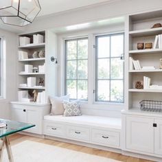 a window seat in the corner of a room with bookshelves and other items