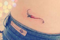 a woman's stomach with a small chili on the side and an arrow tattoo