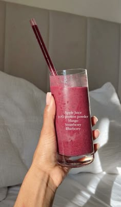 a person holding a glass with a drink in it and two straws sticking out of the top