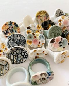 Rows of handmade porcelain rings on a white background. Some are round and painted in blue and white organic line work designs, and some are white and hand textured to look like coral. They all have some shiny gold details Ceramic Rings Handmade, How To Make Porcelain Jewelry, Porcelain Jewellery Contemporary, Paper Porcelain Ceramic Art, Ceramic Jewelry How To Make, Ceramics Rings