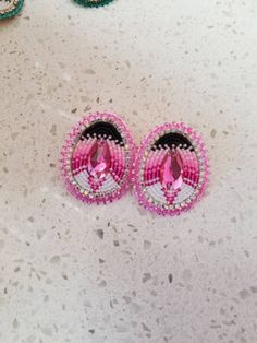 two pairs of pink and black hair clips on a table with other items in the background