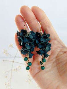 a pair of green flower earrings on a person's hand