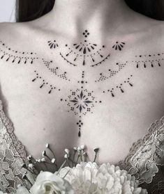 the back of a woman's chest with an intricate design on it and flowers