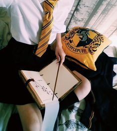 a person wearing a harry potter shirt and tie holding an open book with a wand in it