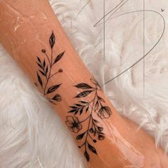 a woman's arm with flowers and leaves tattoo on the left side of her leg