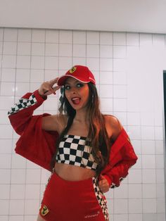 a woman in a red and white checkered top is posing for the camera with her arms behind her head