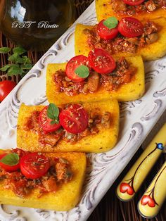 three pieces of bread with tomatoes and meat on them sitting on a plate next to some vegetables