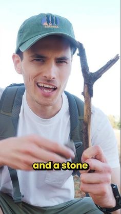 a young man is holding a tree branch and pointing at it with the caption that reads, and a stone