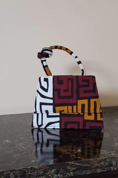 Turn heads with our cute and unique African Print mini bag . This fashionable and easy to carry Afrocentric handbag is perfect for any casual or formal occasion. Pair it up with a solid color outfit to elevate your look! Description: Afrocentric handmade bag with metal chain (chain about 20in) Can be worn as a crossbody bag Made with African wax fabric also known as Ankara Interior is a black compartment Lined with cloth Snap closure Easy to carry and versatile (from casual to formal) Perfect gi Small Bags Diy, African Print Bags, African Inspired Accessories, Painted Purses, Business Clothing, Box Bags, Handmade Leather Bags, Style Staples