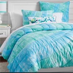 a bed with blue comforter and pillows on it