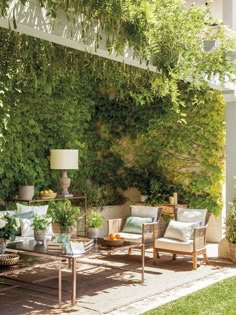 an outdoor living area with couches, chairs and tables in front of a green wall