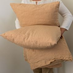 a woman holding two pillows in her hands