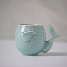 a ceramic fish shaped cup sitting on top of a table