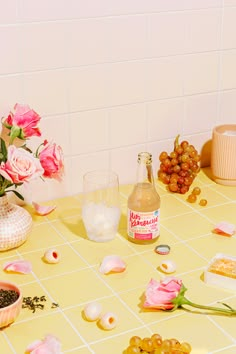 a table topped with lots of food and flowers next to a vase filled with pink roses