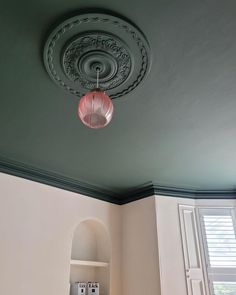 the ceiling in this room is painted green and has a pink lamp hanging from it