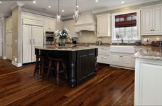 a large kitchen with white cabinets and wood flooring on the hardwood floors is shown